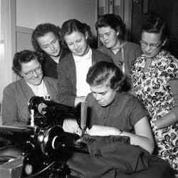 En grupp kvinnor kring en symaskin under en sykurs i Kvistbro. - klicka för att förstora