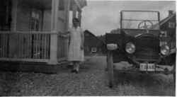 Kvinna framför huvudbyggnaden till Binninge gård med en bil T-Ford med registreringsskylt T2148. - klicka för att förstora