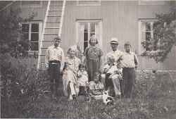 Familjen Karl Andersson framför en träbyggnad - klicka för att förstora