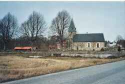 Edsbergs kyrka med gaveln p� kyrkskolan till v�nster och H�glunda g�rd till h�ger i bakgrunden - klicka f�r att f�rstora