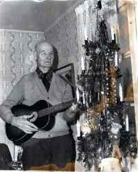 Elof Falk spelar gitarr vid julgranen - klicka för att förstora