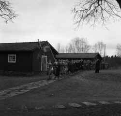 Lottor marscherar med fanor i t�ten och under �verseende av pr�st i h�g hatt. De �r p� v�g mellan Kvistbro f�rsamlingshem och dess flyglar, i riktning mot Kvistbro kyrka. - klicka f�r att f�rstora