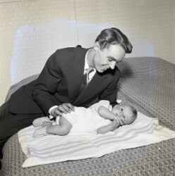 Hans Erik Rickardsson i Fjugesta med hans och Ingers barn på en säng i samband barnets dop - klicka för att förstora