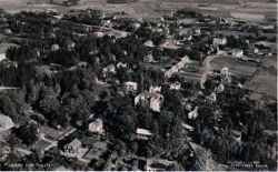 Flygfoto �ver Fjugesta med j�rnv�gen och Storgatan uppe i bild, Letstigen slingrande till h�ger och Tingshuset ungef�r mitt i bild. Uppe i h�gra h�rnet skymtar Tegelbrukets stora byggnader. - klicka f�r att f�rstora