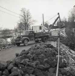 Lastbil och grävmaskin vid ombyggnaden av bron vid Kvistbro kyrka. Bilden är tagen mot Kvistbro kyrka med klockarbostaden till vänster. - klicka för att förstora