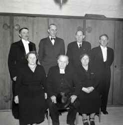 En grupp personer i samband �terinvigningen av Kvistbro kyrka 1955. Mannen i fr�mre raden �r Georg Magnusson, l�ngst bak till h�ger st�r kyrkv�rd Rune Ignell och mannen l�ngst till v�nster i samma rad �r troligen ocks� kyrkv�rd. - klicka f�r att f�rstora