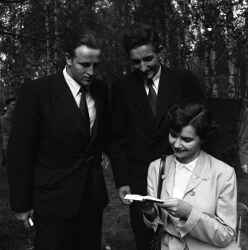 Tv� m�n och en kvinna studerar en liten bok - klicka f�r att f�rstora