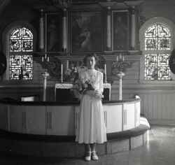Flicka med blommor i koret i Kvistbro kyrka efter konfirmationen påsken 1954 - klicka för att förstora