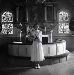 Flicka med blommor i koret i Kvistbro kyrka efter konfirmationen påsken 1954 - klicka för att förstora