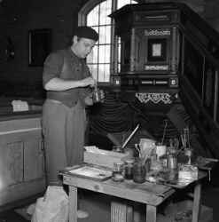 En man med en målarburk i samband med restaureringen av Kvistbro kyrka - klicka för att förstora