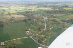 Flygfoto �ver Kvistbro kyrka i riktning mot Gropen och Fjugesta. Nuvarande l�nsv�g 204 slingrar sig bort genom landskapet. - klicka f�r att f�rstora