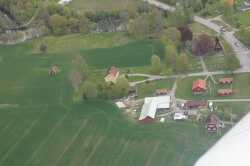 Flygfoto �ver Kvistbro kyrka, pr�stg�rd, f�rsamlingsg�rd och arrendebostad med Svart�n i �vre kanten. - klicka f�r att f�rstora