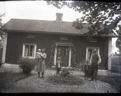 En kvinna, tre barn och en man på grusgången framför ett bostadhus - klicka för att förstora