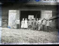En grupp män och två kvinnor framför en ladugård - klicka för att förstora