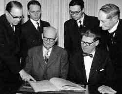 Sex m�n vid kyrkobr�drak�rens jubileum tittar i en bok. Fr�n v�nster Malte Andersson, Bertil K�llstrand, Sigurd Paulsson och Harald Adolfsson i bakre raden. David Andersson och Olle Karlsson i fr�mre raden fr�n v�nster. - klicka f�r att f�rstora