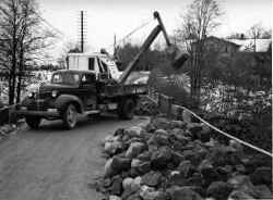 Lastbil och grävmaskin på bron över Svartån vid Kvistbro kyrka med Landslagens skola till höger. - klicka för att förstora