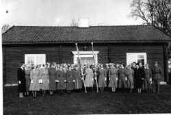 Samling med lottor med fanor framför Kvistbro församlingsgård med manlig militär längst till höger - klicka för att förstora