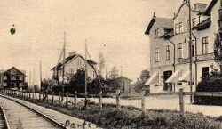 Parti i av Fjugesta i början av 1900-talet med järnvägen i förgrunden samt det senare lantmannamagasinet till vänster och Tidemans hus på Storgatan 1 med järnhandel, café och skoaffär längst till höger - klicka för att förstora