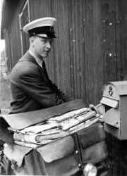 Lantbrevbärare Rudolf Krantz tömmer en brevlåda, som troligen hänger på väggen till Hjalmar Erikssons gård i Västra Hulvik. - klicka för att förstora